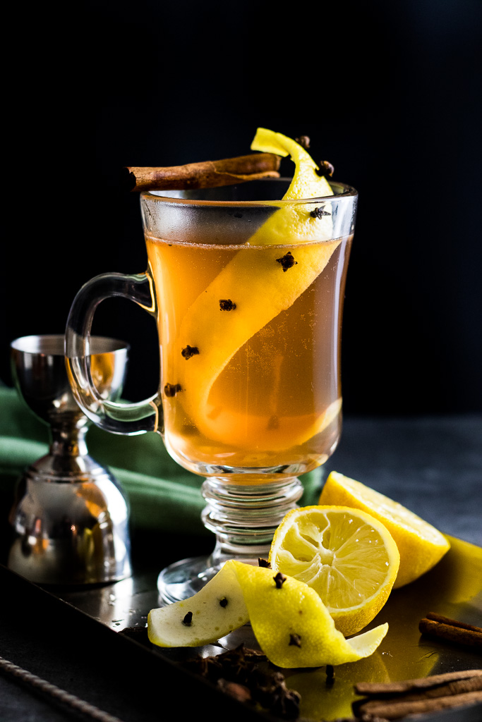 Easy Hot Toddy in a glass much with a lemon zest impaled with whole clove