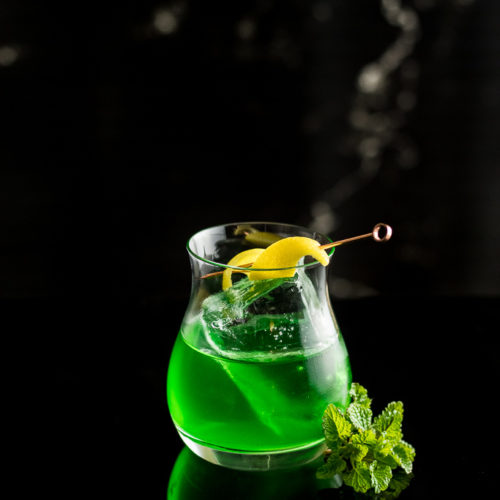 Pissed Leprechaun - Green Suze Cocktail on ice with lemon twist