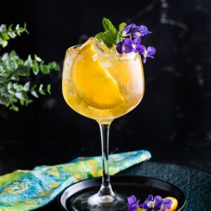 Spring Bourbon Spritz with orange slice and mint as garbage, served over ice in a large wine glass.