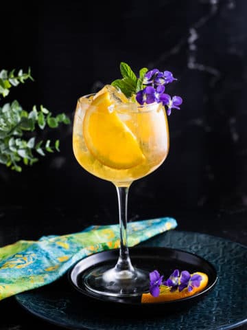 Spring Bourbon Spritz with orange slice and mint as garbage, served over ice in a large wine glass.