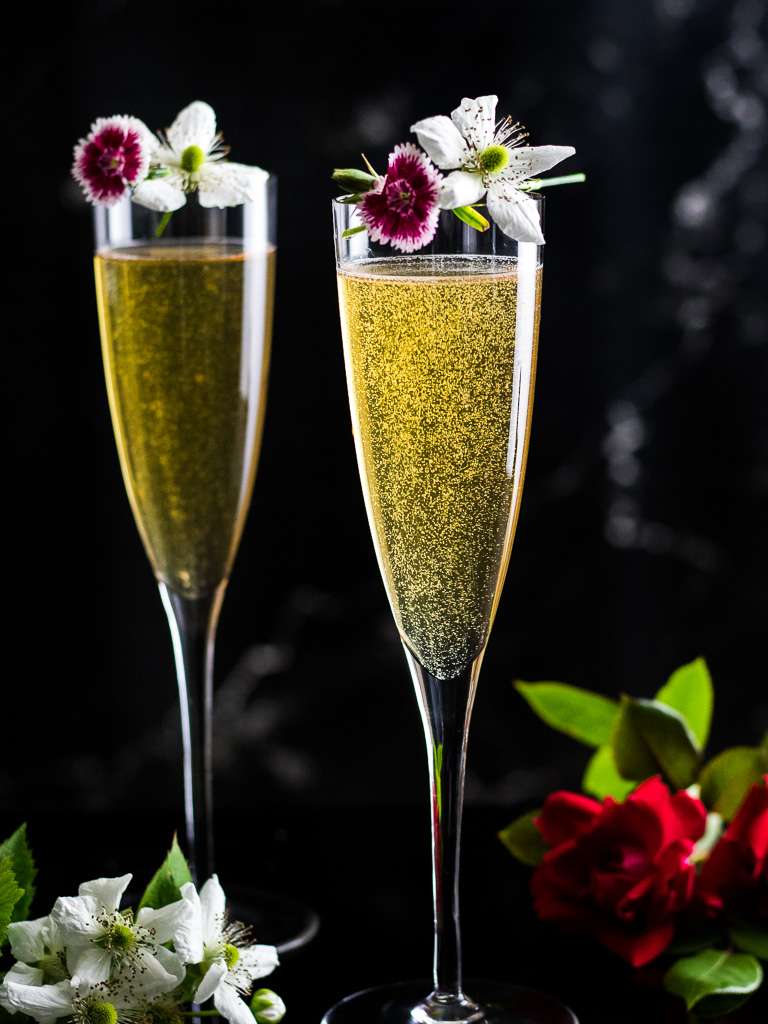Bourbon Mimosa - two champagne flutes with cocktail and fresh flower garnish