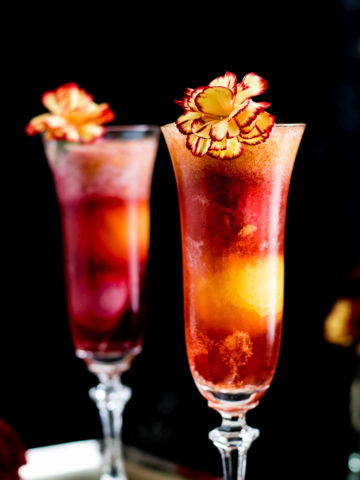 Bourbon and Bubbles Sorbet Cocktail for Mother's Day in two champagne flutes garnished with yellow and red mum