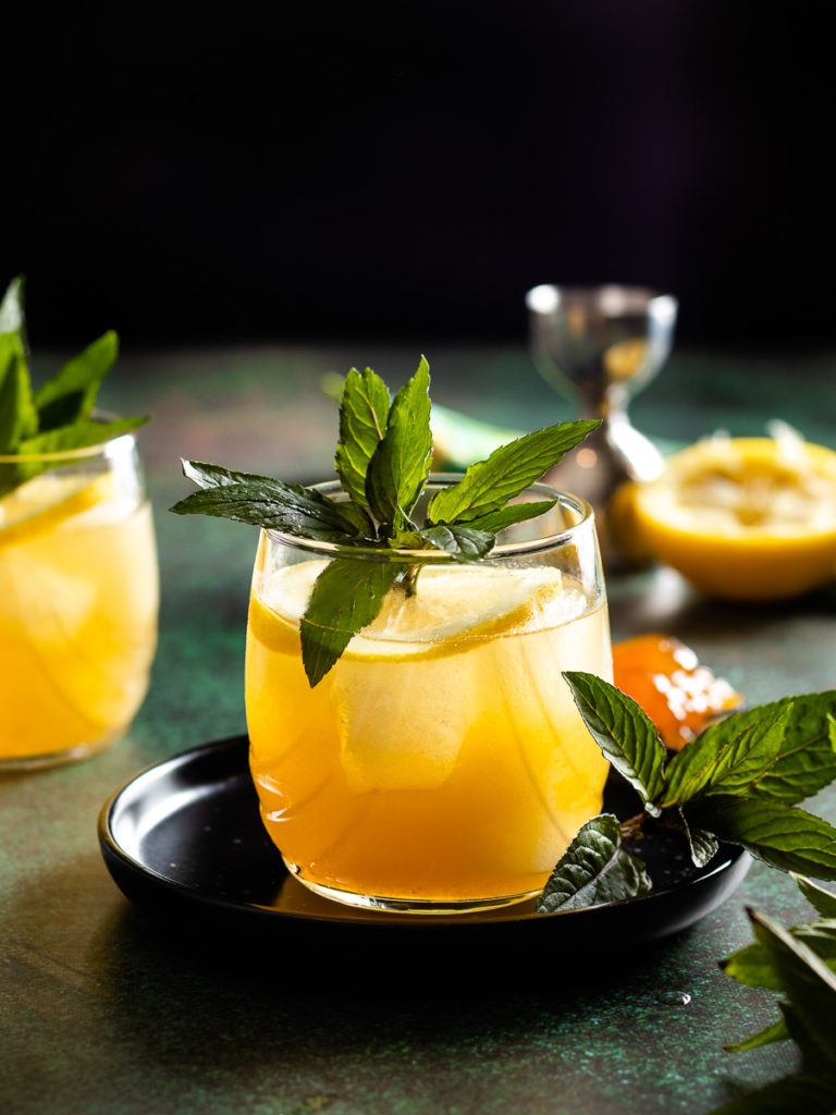 bourbon limoncello cocktail with lemon wheel and mint garnish - 2 glasses, spoon of preserves