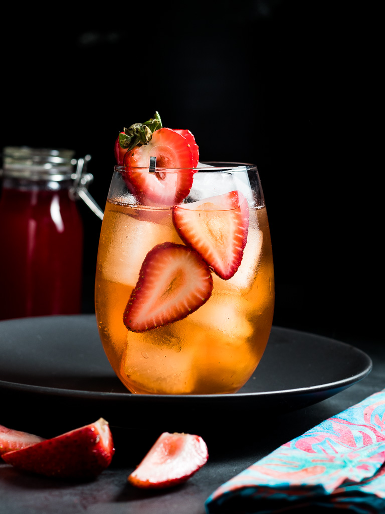 strawberry old fashioned over ice with a sliced strawberry garnish
