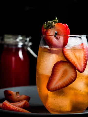 strawberry old fashioned over ice with a sliced strawberry garnish