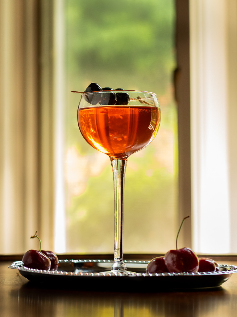 Aperol Manhattan - Little Italy in a coupe glass with a cherry garnish