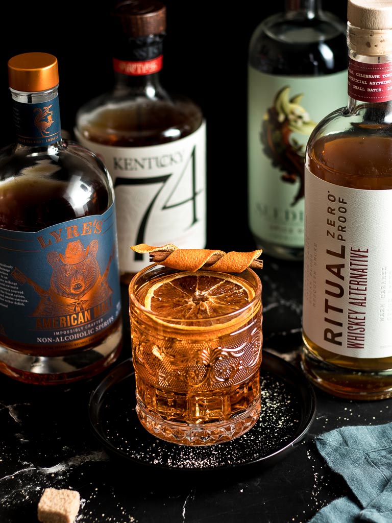 Non-Alcoholic Whiskey Alternatives for Whiskey Mocktails - Bottles of Lyre's, Seedlip Spice, Ritual Zero Proof and Kentucky 74 and a cocktail