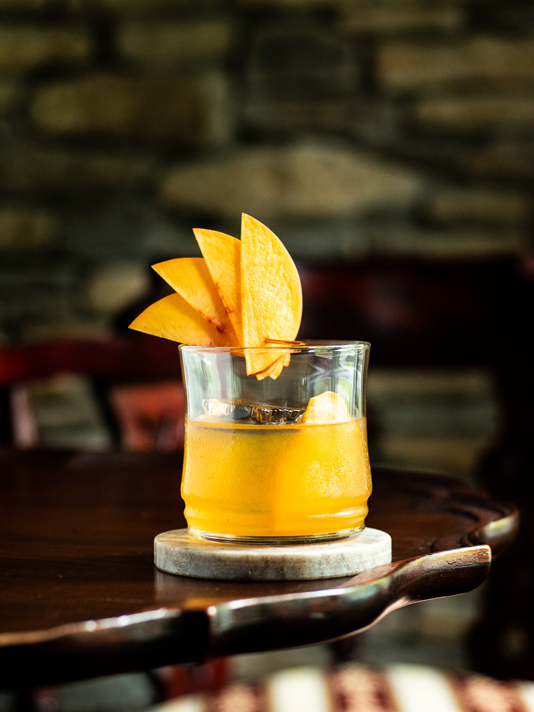 Peach Old Fashioned on a table with a peach fan garnish