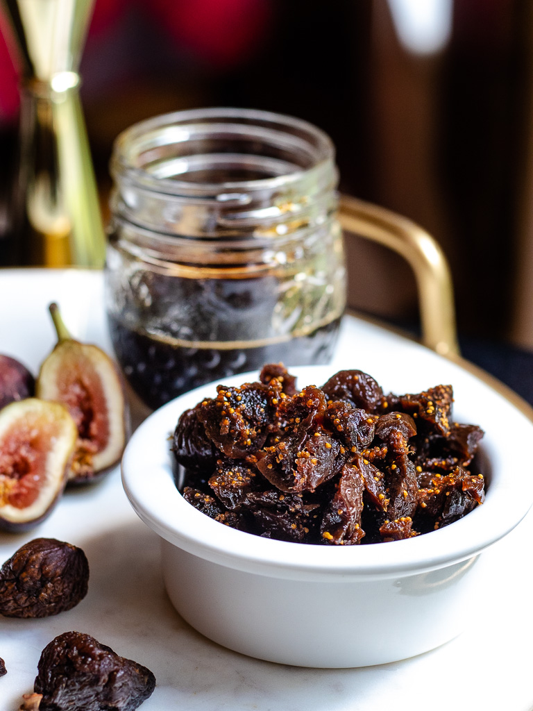 Homemade Fig Syrup in a jar with dried and fresh figs on a tray