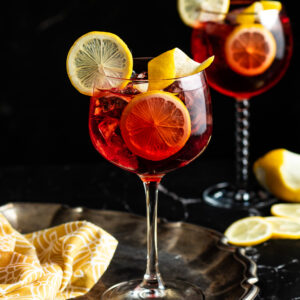 Negroni and Tonic in a wine glass garnished with a lemon wheel and lemon twist