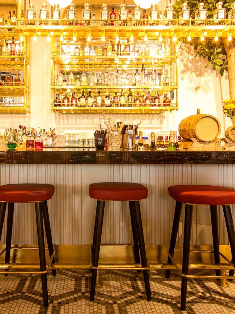 source of cocktail inspiration - a cocktail bar with gold bar and red stools
