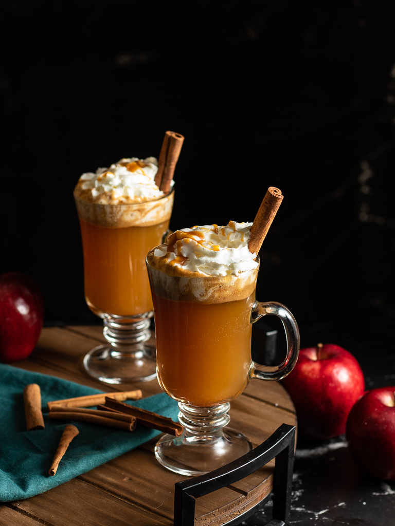 Hot Buttered Cider in a mug topped with whipped cream and a cinnamon stick