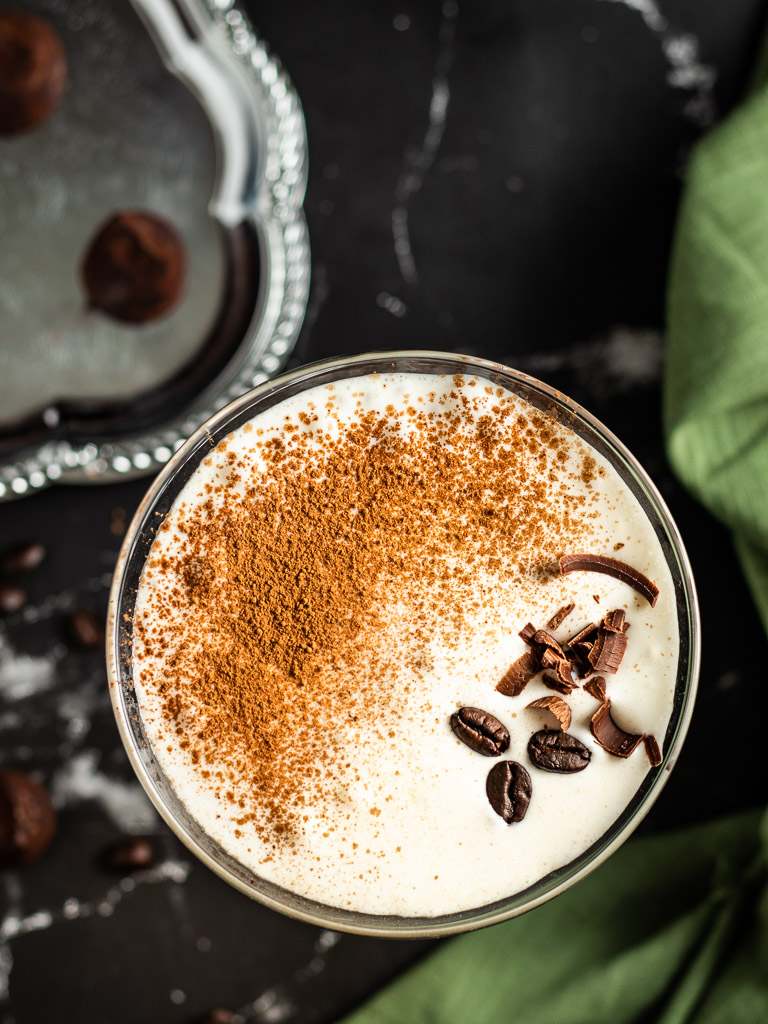 Tiramisu cocktail in a glass garnished with cocoa coffee beans and chocolate shavings