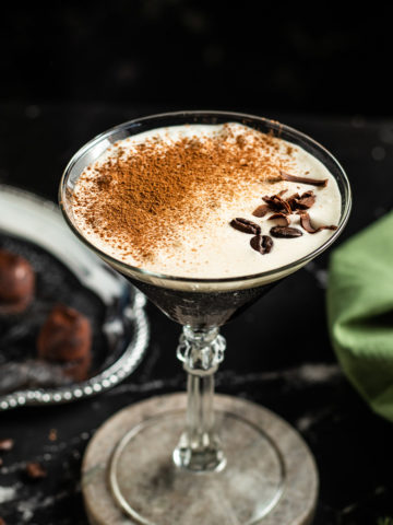 Liquid Tiramisu cocktail in a martini glass garnished with cocoa coffee beans and chocolate shavings