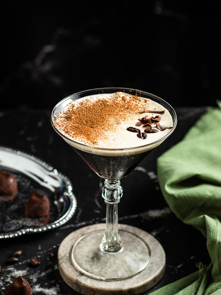 Tiramisu martini cocktail made with rum, in a martini glass topped with espresso beans and cocoa powder