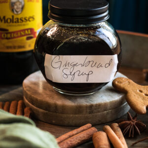 gingerbread syrup for cocktails with spices and cookies surrounding it
