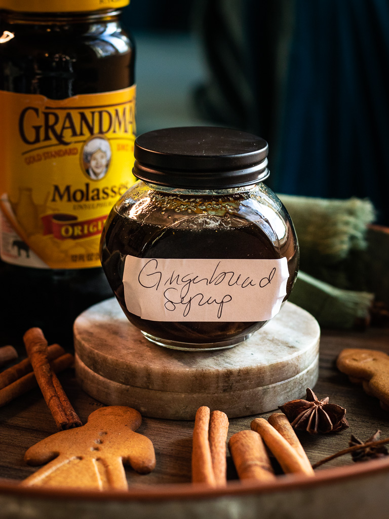 gingerbread syrup for cocktails with spices and cookies surrounding it