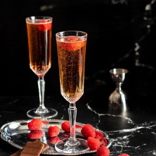 New Years' Cocktail - Two champagne flutes with cocktail and raspberry garnish