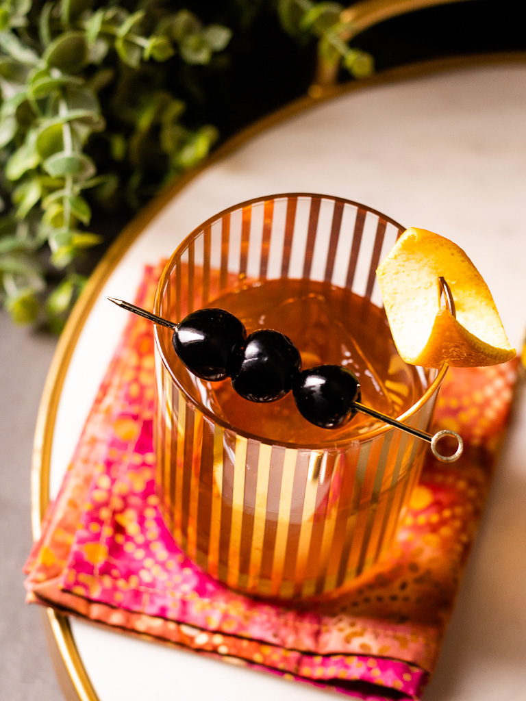 Sherry Old Fashioned in a gold accent glass with orange peel and cherries