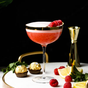 Raspberry Sour in a coupe glass with foam and raspberry garnish