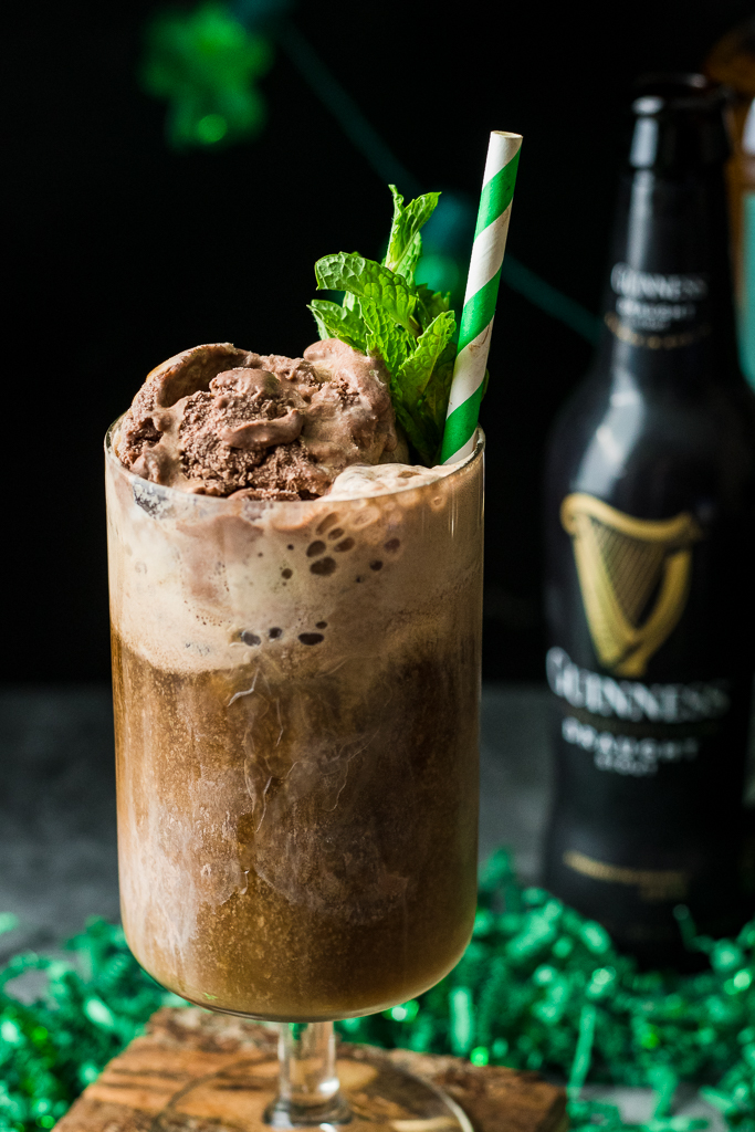 Beer float in tall glass with chocolate ice cream, mint, guinness stout and irish whiskey, with straw.