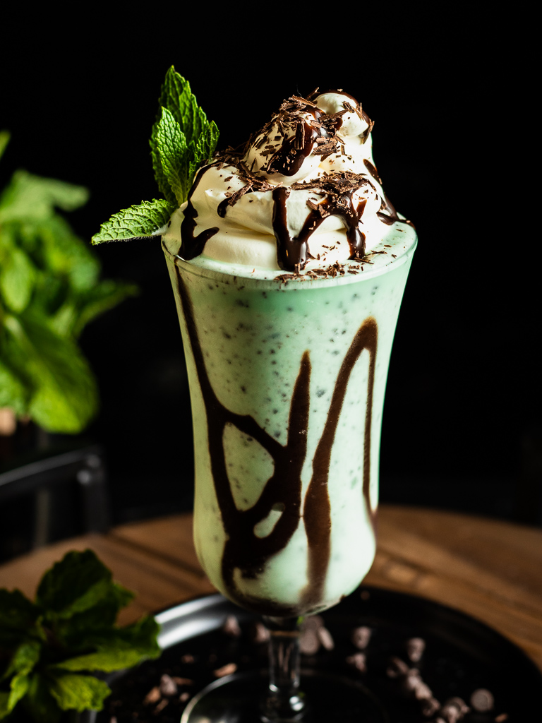Mint Julep Milkshake in a glass with chocolate drizzle, whipped cream and chocolate savings