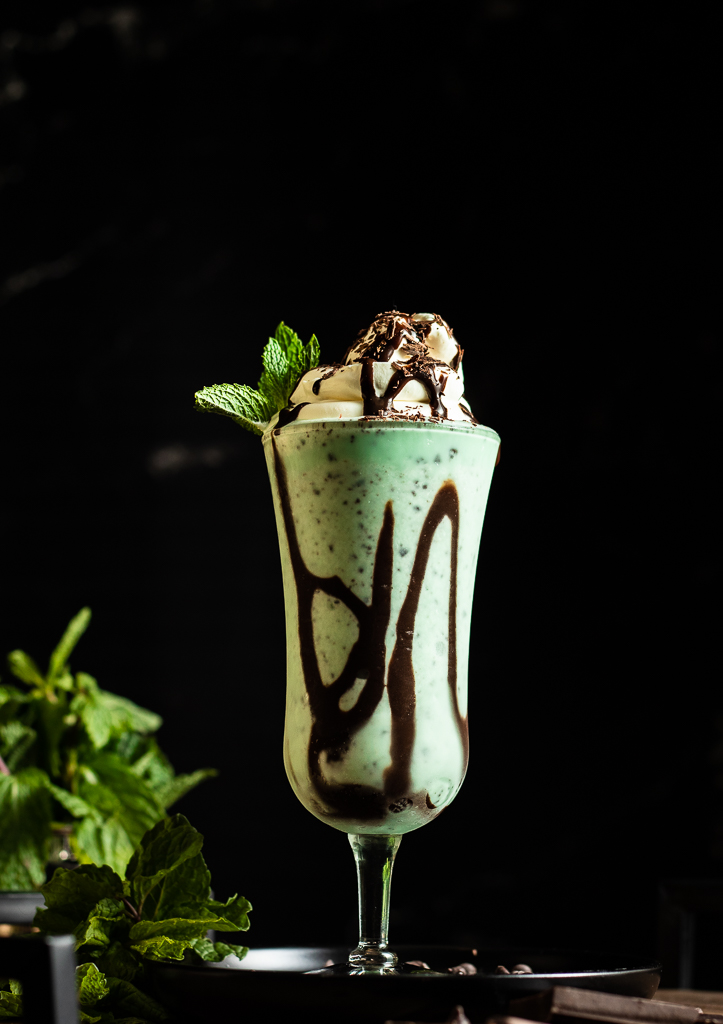 Mint Julep Milkshake in a glass with chocolate drizzle, whipped cream and chocolate savings
