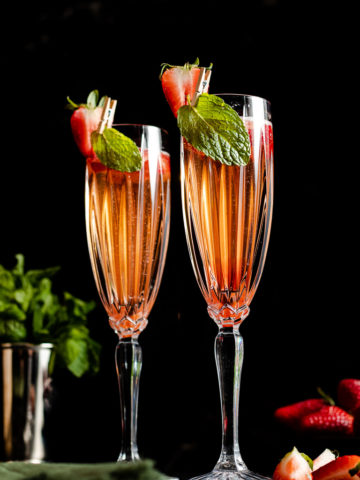 champagne derby cocktail, bourbon, bubbles, strawberry and mint in two champagne flutes