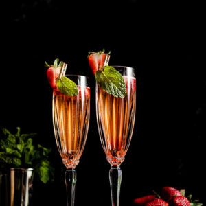 champagne derby cocktail, bourbon, bubbles, strawberry and mint in two champagne flutes