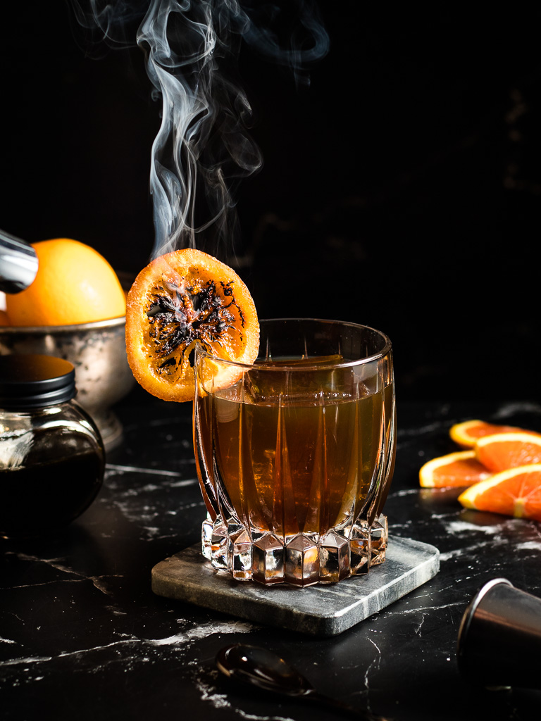 Sorghum Old Fashioned in a rocks glass with a charred orange wheel