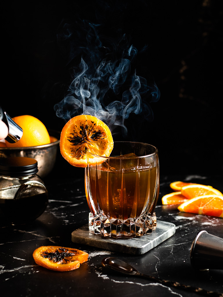 Sorghum Old Fashioned in a rocks glass with a charred orange wheel