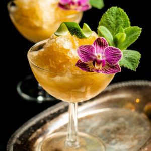 Bourbon Slushies on a chilled coupel glass with edible flower garnish