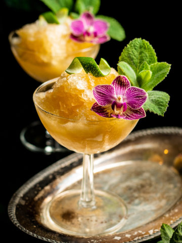 Bourbon Slushies on a chilled coupel glass with edible flower garnish