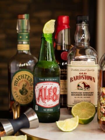 Bottle of Ale-8 One with a lime in it and bourbon bottles - Kentucky Ranch Water