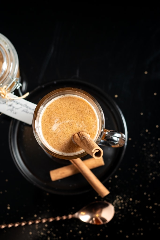 hot buttered rum in a glass mug with a cinnamon stick as garnish