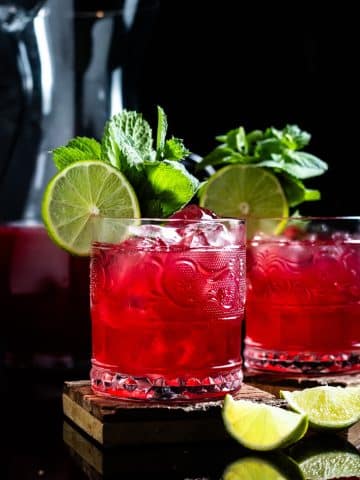 pomegranate margarita in a low rocks glass with lime wheel and mint for garnish