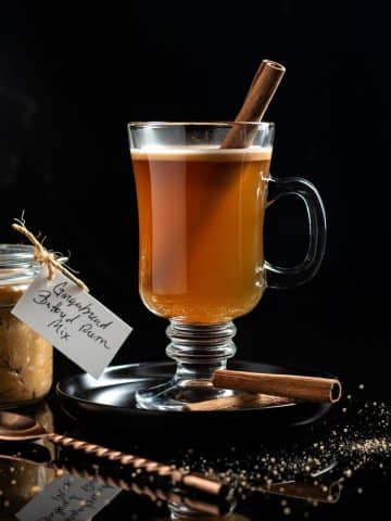 hot buttered rum in a glass mug with a cinnamon stick as garnish
